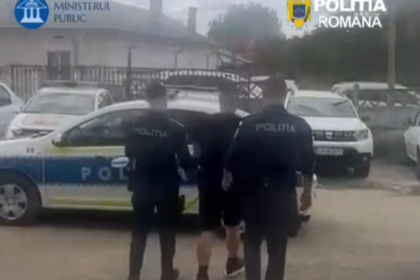 Three Romanian police officers in dark uniforms walk beside a marked police car in a parking area (police operation scene).