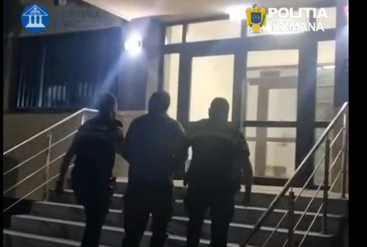 Three men walking up an outdoor staircase toward a glass door at night, railing on both sides.