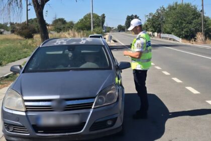 Police officer in a bright safety vest talks to the driver through the car window during a daytime traffic stop on a rural road