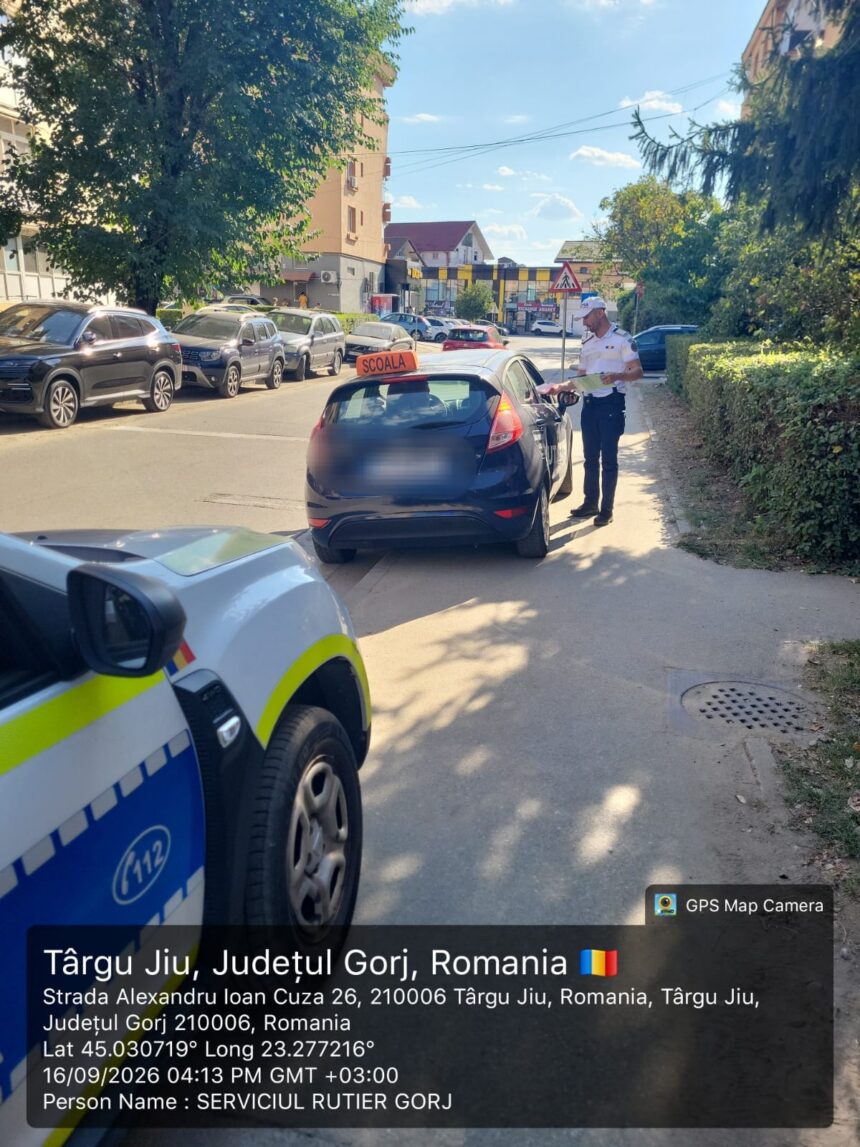 Police officer in a white uniform checks documents with a driver beside a blue car on a sunny street lined with parked cars.
