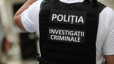 Back view of a Romanian police officer wearing a bulletproof vest labeled POLIȚIA and INVESTIGAȚII CRIMINALE (Criminal Investigations).