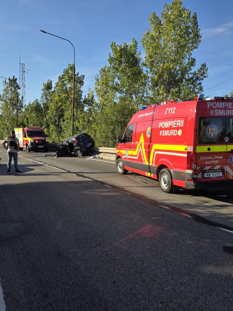 Red emergency response van on a highway near a wrecked car and debris on the road, with responders nearby and green trees in the background.