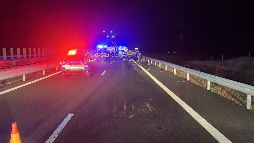 Nighttime highway crash scene with police car, ambulance, and firefighters tending to an incident in the distance with flashing lights.