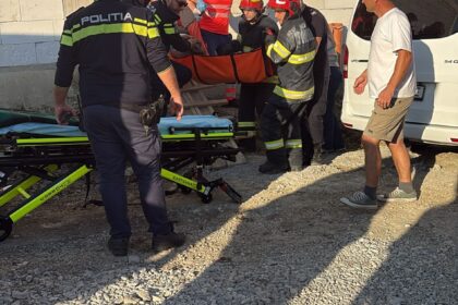 Emergency responders and police carry an injured person on a stretcher outside a partially built concrete building.