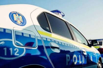 Blue and white police car with a crest on the door and an emergency light on the roof, 'Politia' visible on the side.