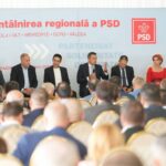 Panel of politicians seated on stage during a conference, backdrop with PSD logo and Romanian text, audience in foreground