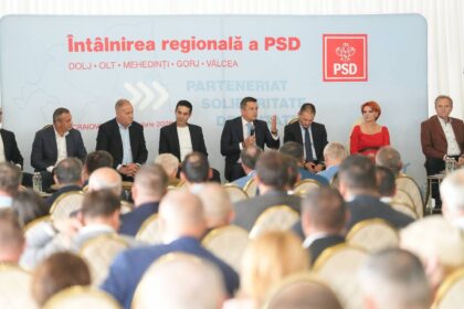 Panel of politicians seated on stage during a conference, backdrop with PSD logo and Romanian text, audience in foreground