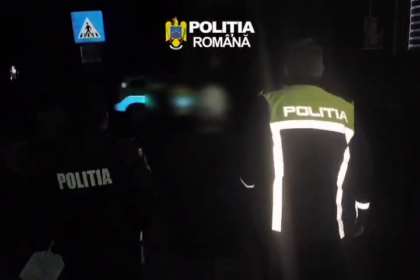 Romanian police officers in reflective jackets at night, with POLITIA marks visible on their backs.