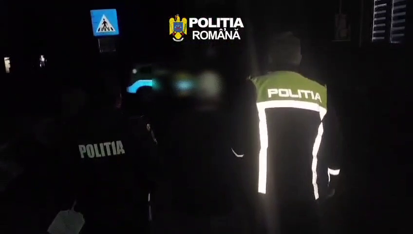 Romanian police officers in reflective jackets at night, with POLITIA marks visible on their backs.