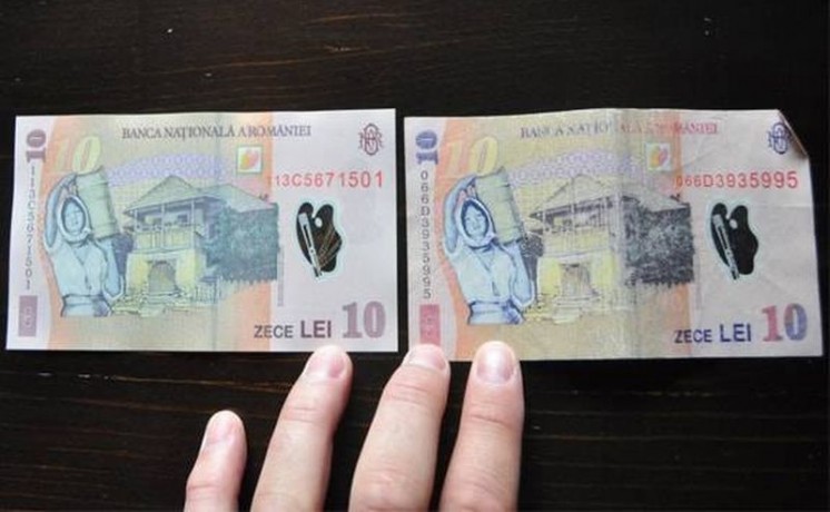 Two ten‑lei Romanian banknotes laid side by side on a dark surface, with a few fingers visible at the bottom.