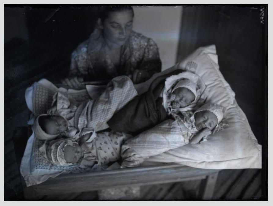 4 copii floru icoana 854416362_4778983635580540_3596266629189038597_n - Jurnalul Olteniei – Știri din Craiova și Oltenia A woman sits beside a crib with three newborn babies wrapped in blankets on the bedding nearby.