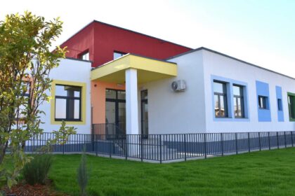 Colorful, modern building with white, yellow, blue window frames and a green lawn in front