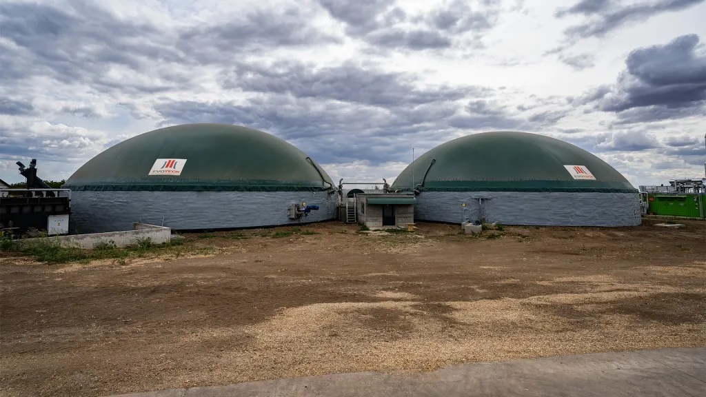 Agro-Chirea-4 unu - Jurnalul Olteniei – Știri din Craiova și Oltenia Two large green domed industrial tanks connected by a small platform under a cloudy sky on a dirt yard.