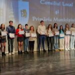 Group of young people on a stage holding certificates during a local government awards ceremony.