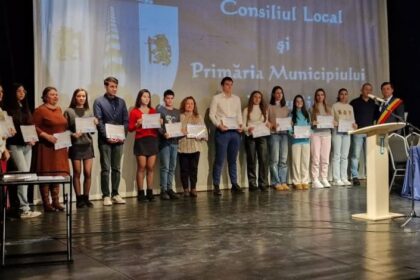 Group of young people on a stage holding certificates during a local government awards ceremony.