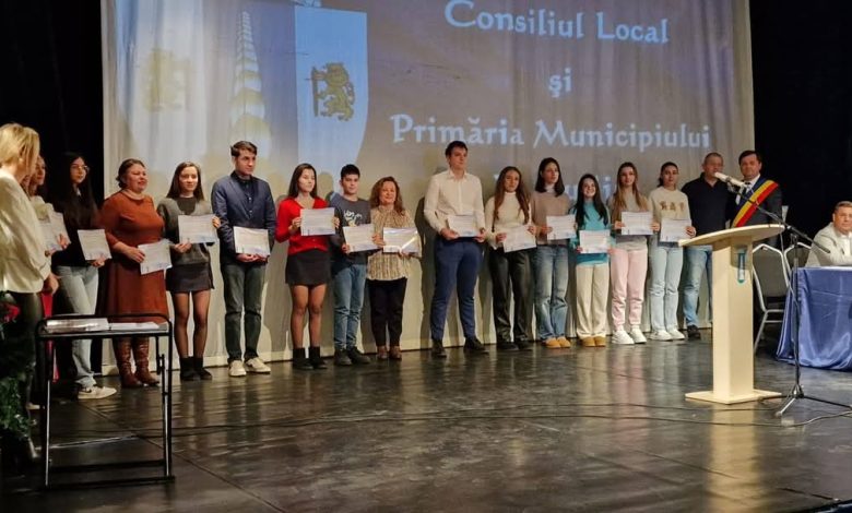 Group of young people on a stage holding certificates during a local government awards ceremony.