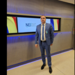 Man in a blue suit and tie standing in front of a Nuclear Energy Institute display.