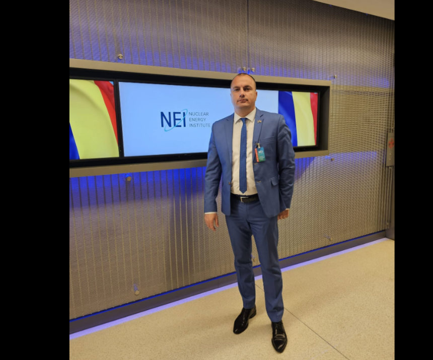 Man in a blue suit and tie standing in front of a Nuclear Energy Institute display.