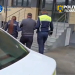 Two Romanian police officers escort a man up exterior stairs toward a building, with Ministerul Public and Politia Romana logos visible.