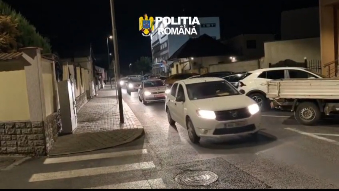 Nighttime street scene with several cars driving in a line, police emblem 'Poliția Română' overlaid at the top left.