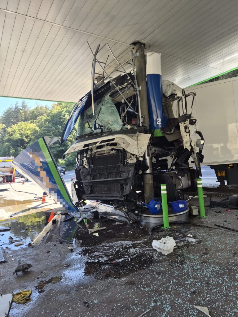 WhatsApp Image 2026-10-06 at 135414 - Jurnalul Olteniei – Știri din Craiova și Oltenia Blue semi truck crashed into a concrete pillar at a gas station; windshield shattered and cab severely damaged in the impact.