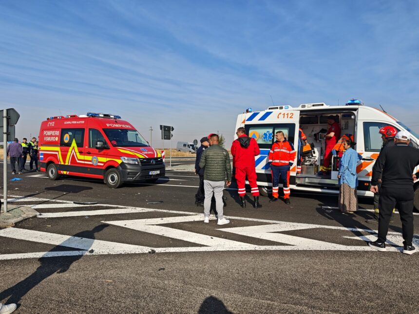 Group of emergency responders and bystanders beside two ambulances on a road under a clear blue sky on scene