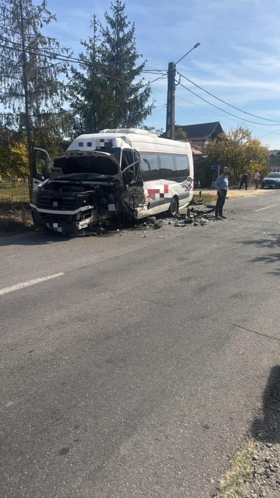 White minibus with severe front-end damage parked on a street, hood open and debris scattered nearby.