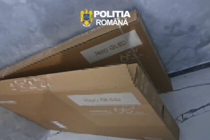 Two brown cardboard boxes stacked on a blue-tiled floor with blurred shipping labels; police watermark 'Politia Romana' in the corner.