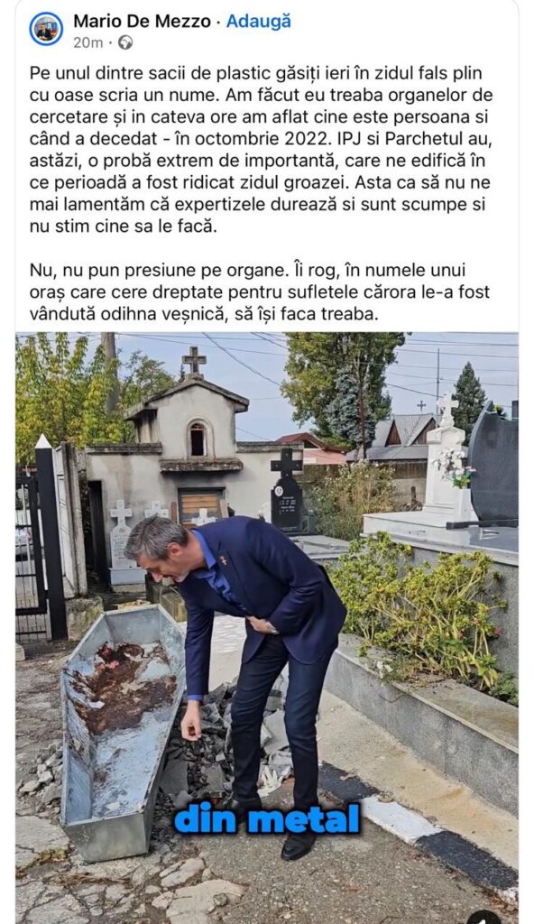 Bărbat în costum albastru inspectând resturi metalice într-un cimitir, lângă o ladă metalică plină de fragmentații.