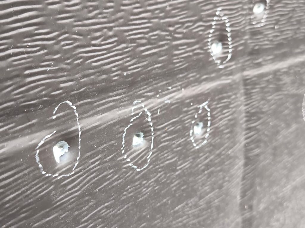 WhatsApp Image 2026-10-22 at 152110 - Jurnalul Olteniei – Știri din Craiova și Oltenia Close-up of a dark wooden plank with white chalk circles around small holes or screws