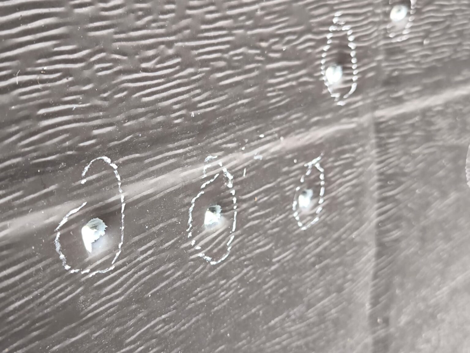 WhatsApp Image 2026-10-22 at 152110 - Jurnalul Olteniei – Știri din Craiova și Oltenia Close-up of a dark wooden plank with white chalk circles around small holes or screws