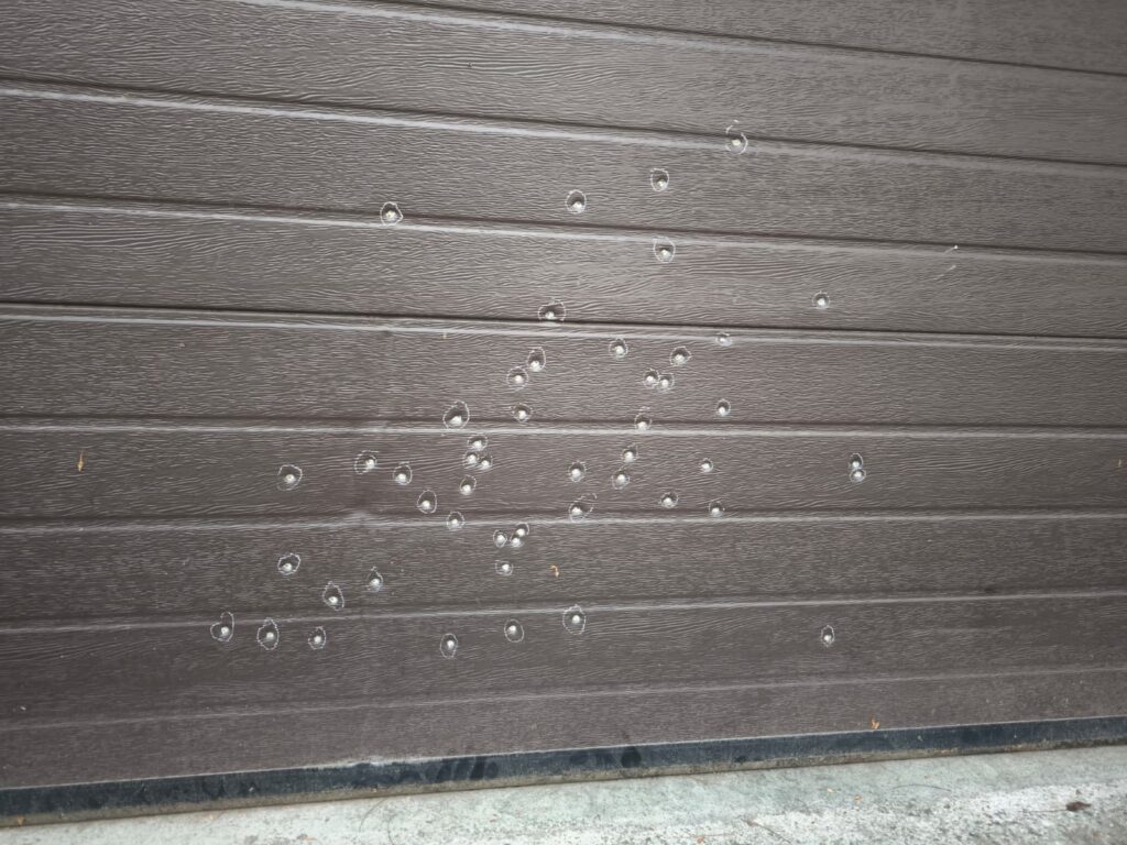 WhatsApp Image 2026-10-22 at 152113 - Jurnalul Olteniei – Știri din Craiova și Oltenia Close-up of scattered water droplets on a dark brown wooden deck surface with visible plank grooves.