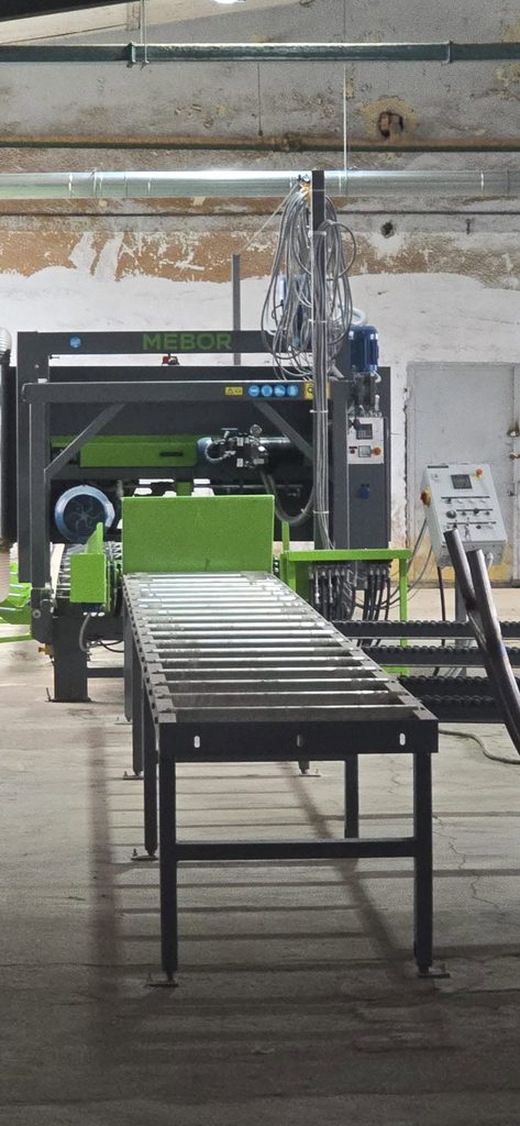 Industrial conveyor belt system in a factory, with green machinery and overhead cables.