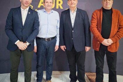 Group portrait of four men standing side by side indoors, dressed in blazers and smart casual wear, in front of a dark backdrop with a yellow ADR logo and stars.