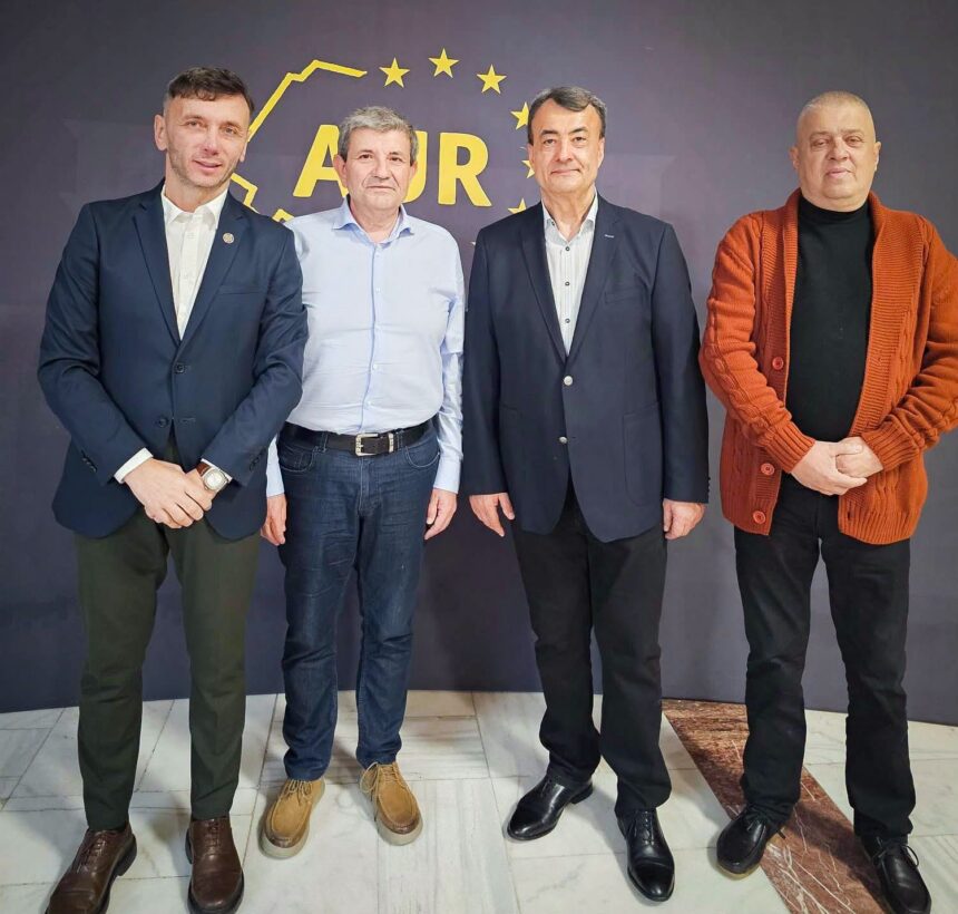 Group portrait of four men standing side by side indoors, dressed in blazers and smart casual wear, in front of a dark backdrop with a yellow ADR logo and stars.
